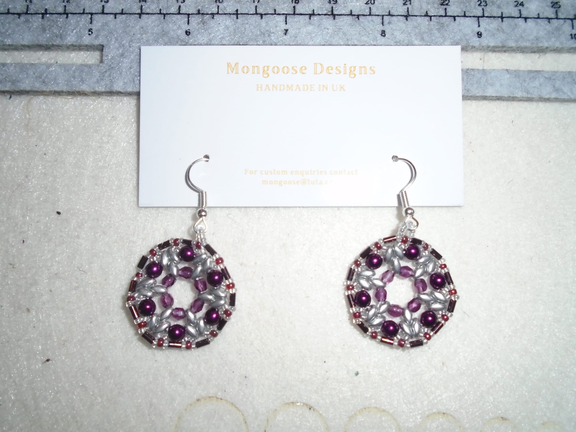 Delicate circular earrings in burgundy and silver, using several different types of bead.