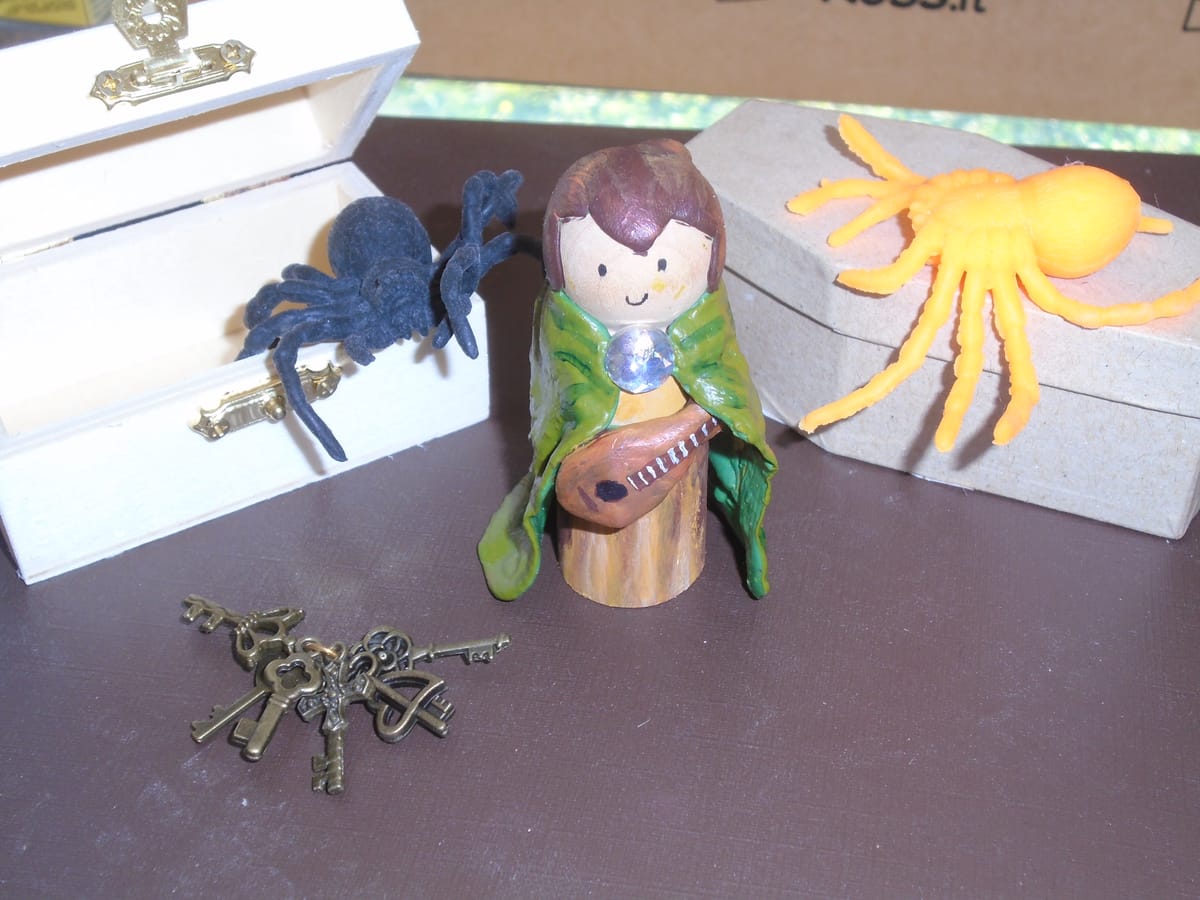 An assortment of roleplaying props, including a bard figure, two spiders, some keys, a treasure chest, and a coffin.