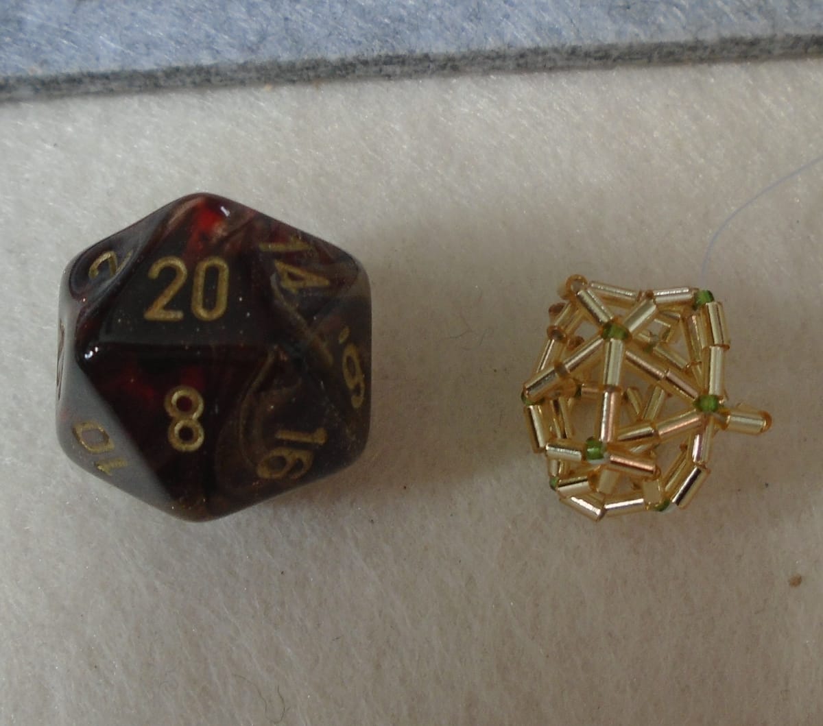 Left: d20 die. Right: attempted, and very wonky, icosahedron (technically the same shape) made from beads.