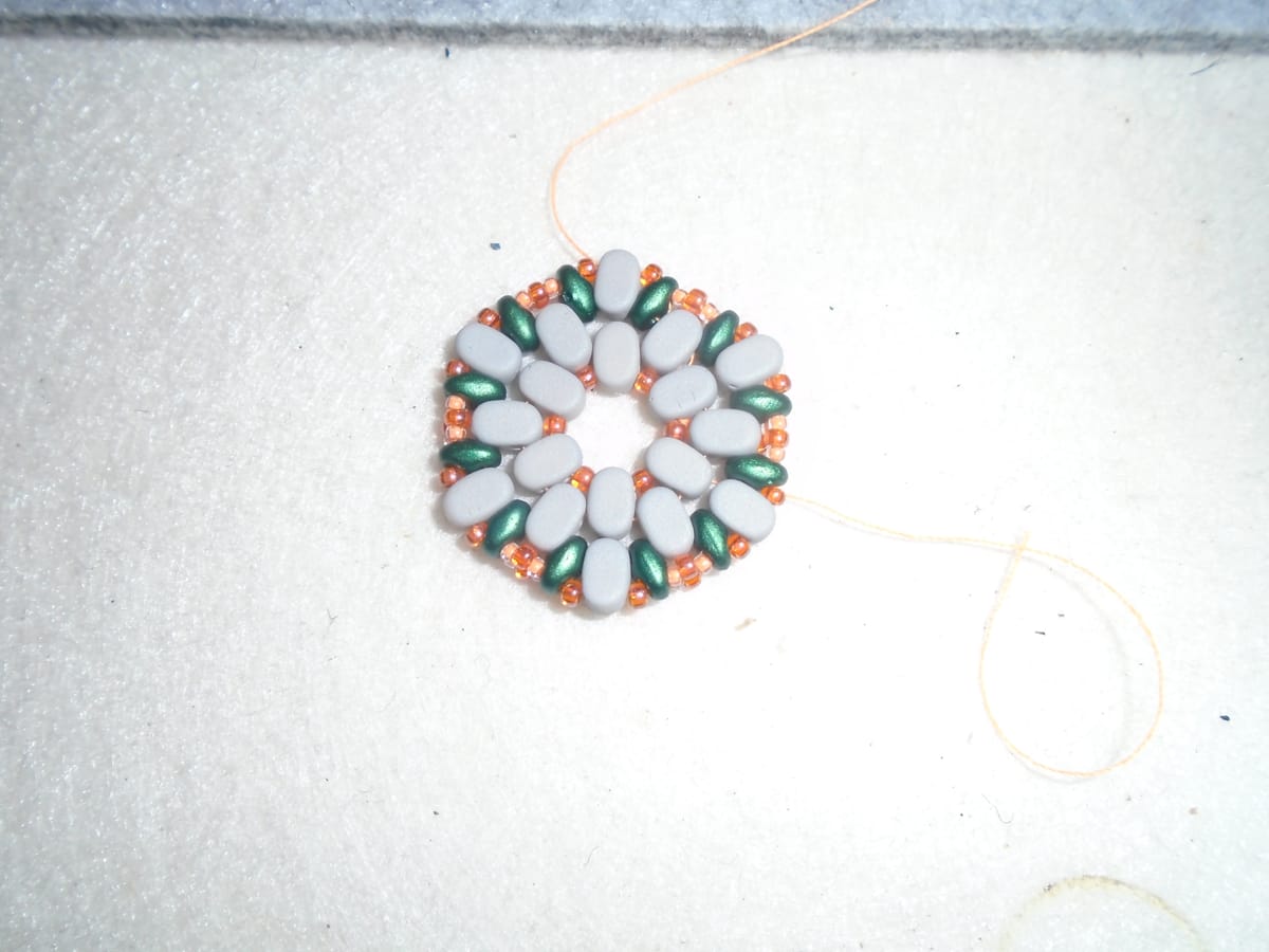 Not an earring, just the beady bit.  It's made mostly from grey oval beads, with a few others in green and orange.