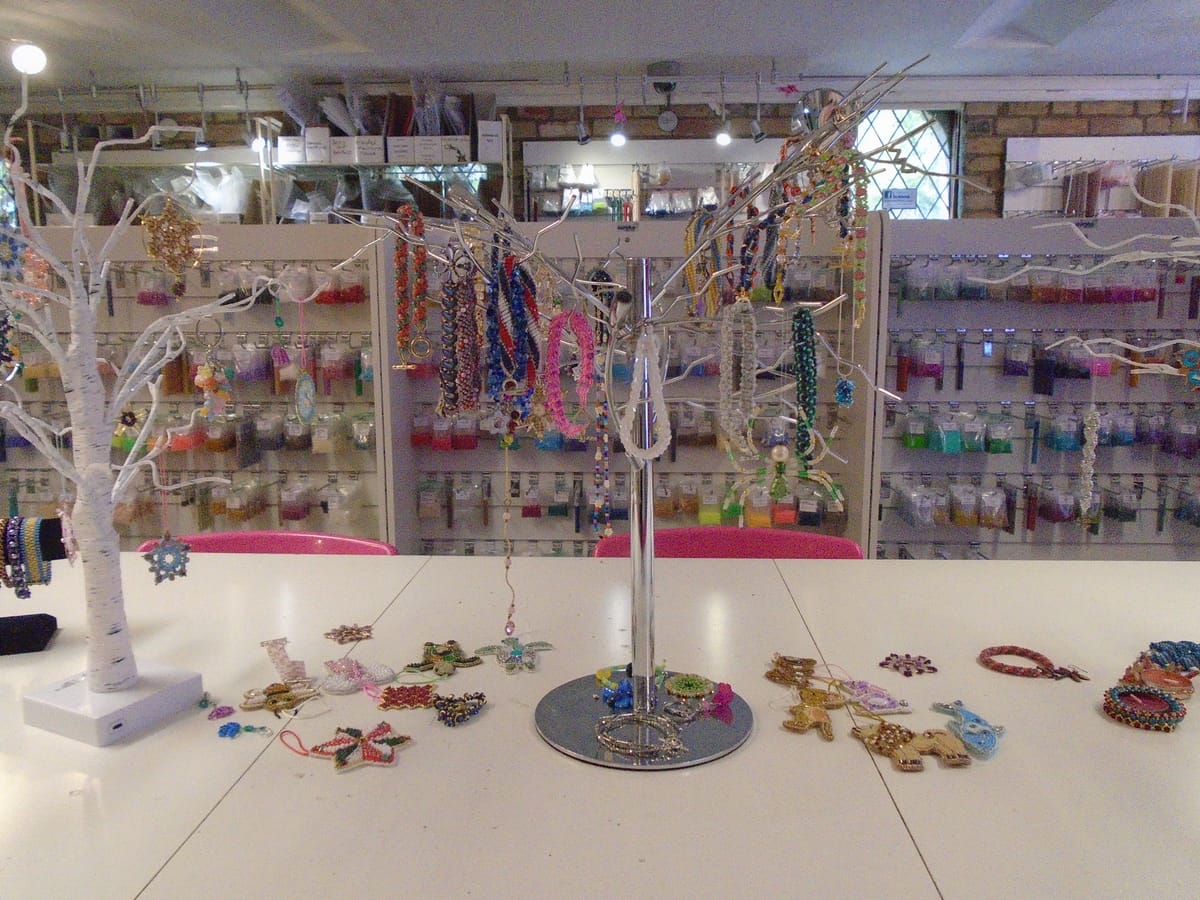 A table with two display trees hung with bead jewellery and ornaments. There are more lying on the table.