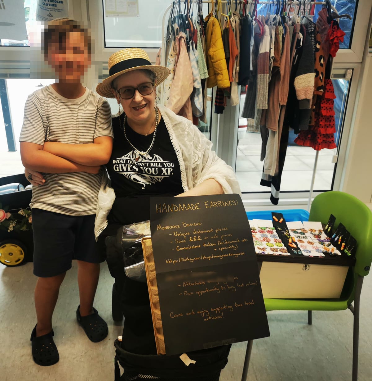 Hezekiah (pixellated) and me with our earrings and the placard. For some reason there's a clothes rail behind us.