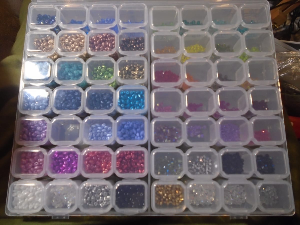 Double pill box with 56 compartments; on the left are slightly larger 2-hole beads, and on the right small glittery ones.