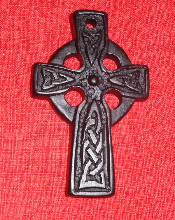 Very dark brown Celtic cross with knotwork and background circle, shown against a red linen-look fabric.