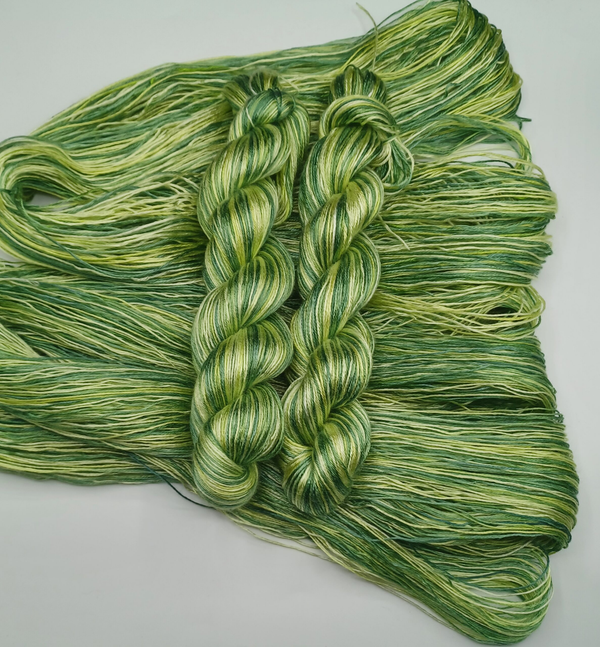 Hand-dyed yarn in a spectrum of colours ranging from yellow to dark green.