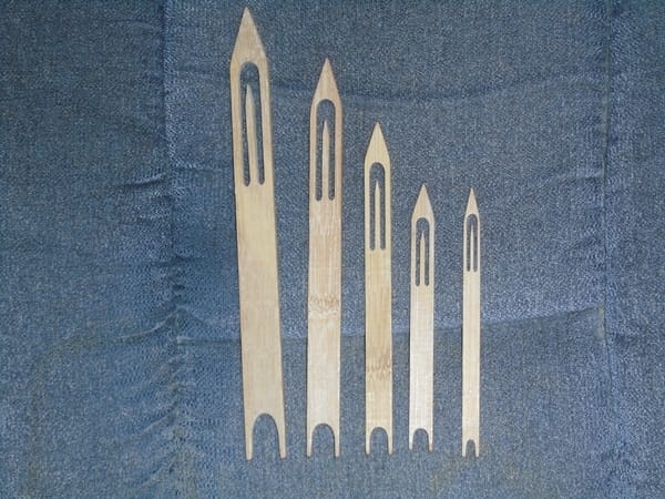 Five traditionally styled boat-shaped bamboo netting needles in sizes decreasing from left to right.
